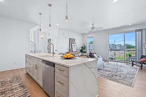 White waterfall island with dishwasher and pendant lights at The Flats at West Glen Apartments, West Des Moines, 50266