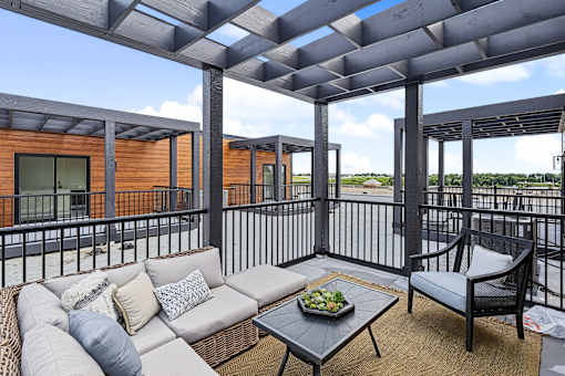 Outdoor patio with gray sectional and waterfront views at The Flats at West Glen Apartments, Iowa