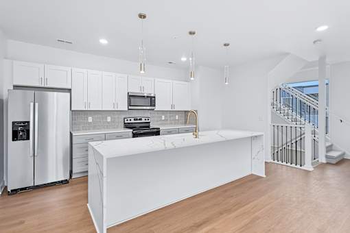 White kitchen island with marble countertop and pendant lights at The Flats at West Glen Apartments, West Des Moines, Iowa