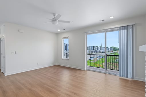 Empty living room with balcony and ceiling fan at The Flats at West Glen Apartments, West Des Moines