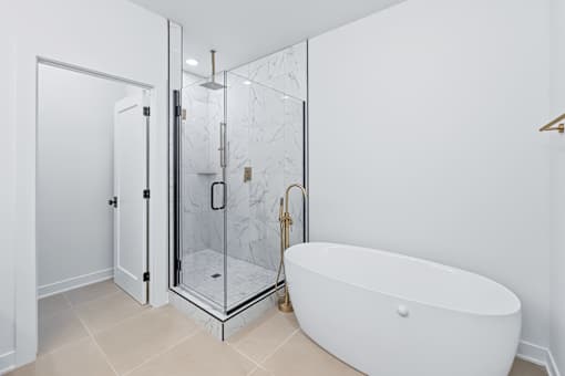 Freestanding soaking tub with gold floor mount faucet at The Flats at West Glen Apartments, Iowa, 50266