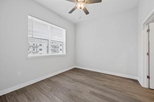A room with a ceiling fan and a window with blinds.