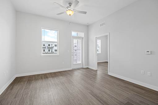 A room with a ceiling fan and wooden flooring.