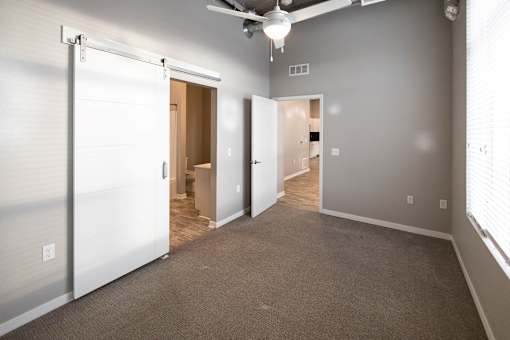 an empty living room with a closet and a door to a bathroom at Velocity Apartments, Iowa