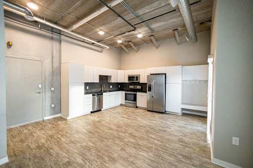 an empty kitchen with a wood floor and white cabinets and stainless steel appliances at Velocity Apartments, Iowa, 50309