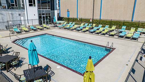a swimming pool with lounge chairs and umbrellas near a building at Velocity Apartments, Des Moines, IA, 50309