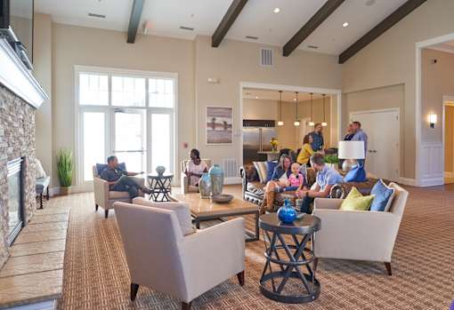 a group of people sitting in a living room with a fireplace at The Winhall of Williams Pointe Apartments, Waukee, IA