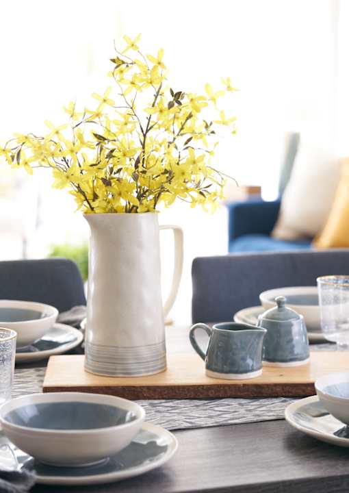 a table with a vase with yellow flowers on it at The Winhall of Williams Pointe Apartments, Waukee, IA
