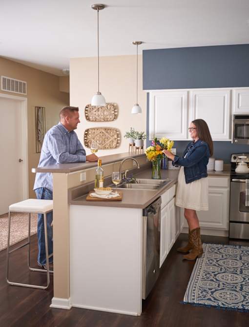 a man and a woman standing at a kitchen island at The Winhall of Williams Pointe Apartments, Waukee