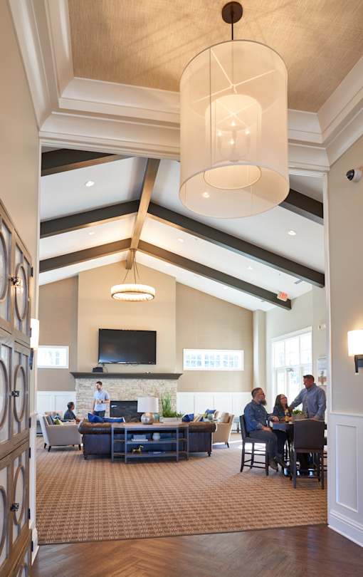 a large lobby with people sitting at tables and chairs at The Winhall of Williams Pointe Apartments, Waukee, IOWA