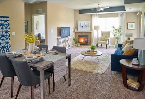 a living room with a table and chairs and a fireplace at The Winhall of Williams Pointe Apartments, IOWA, 50263