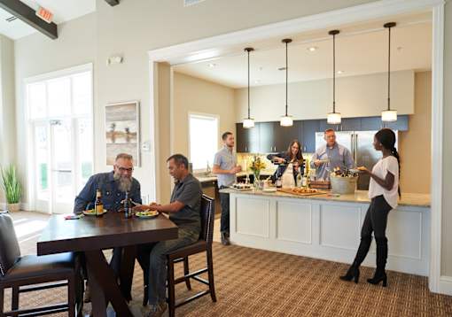 a group of people sitting around a table in a kitchen at The Winhall of Williams Pointe Apartments, Waukee, 50263