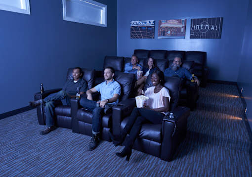 a group of people sitting in a living room watching a movie at The Winhall of Williams Pointe Apartments, Waukee, IA, 50263