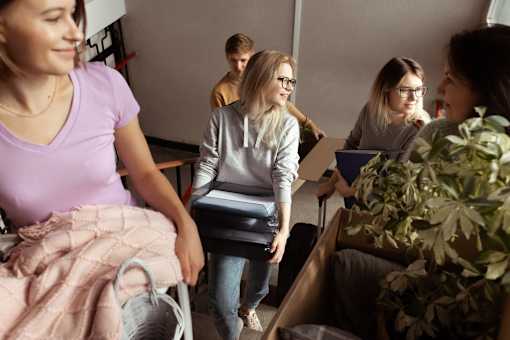 A group of people are gathered in a room, with one person holding a suitcase.