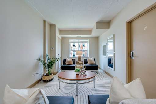 A living room with a round table and striped carpet.