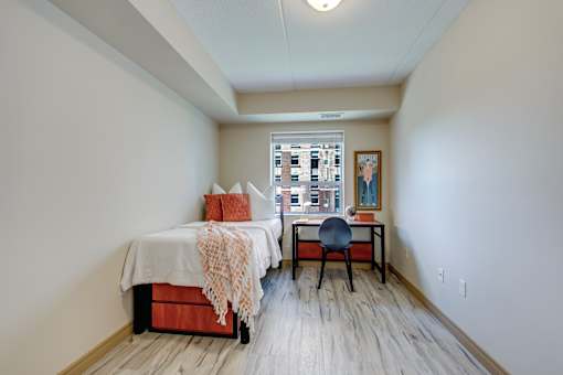 A bedroom with a bed, desk, and chair.