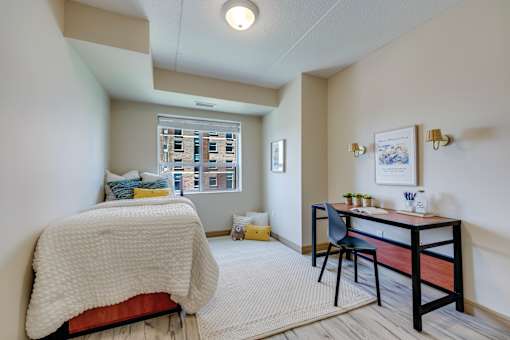 A bedroom with a bed, desk, and chair.