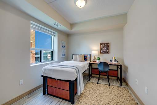 A bedroom with a bed, desk, and chair.