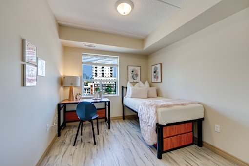 A bedroom with a bed, desk, and chair.
