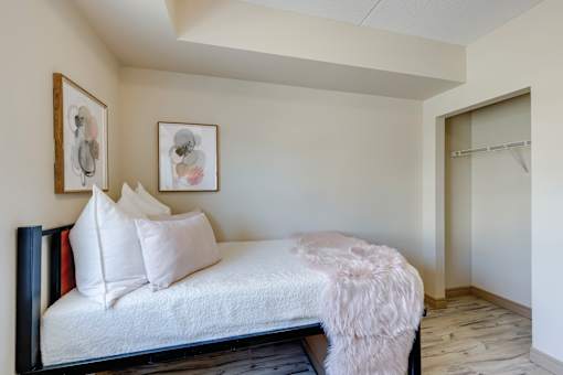 A bedroom with a bed, pillows, and pictures on the wall.