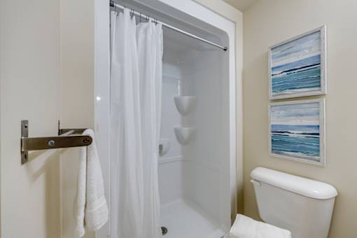 A white bathroom with a shower curtain and a towel hanging on a towel rack.