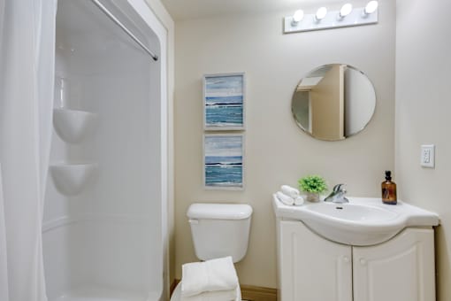 A white bathroom with a toilet, sink, and mirror.