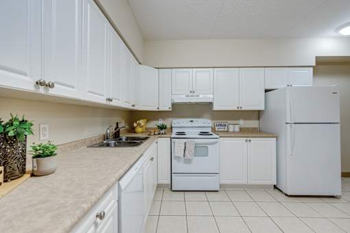 A white kitchen with a sink, stove, and refrigerator.