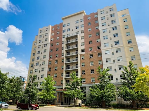 A tall apartment building with a red car parked in front.