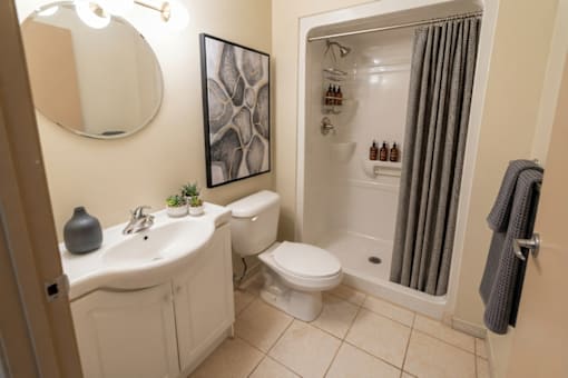 A bathroom with a white sink and toilet, a grey towel, and a mirror.