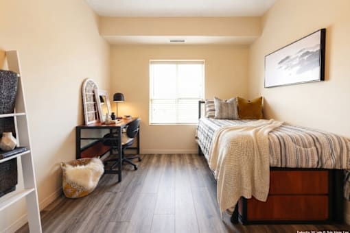 A bedroom with a bed, desk, chair, and a cat.