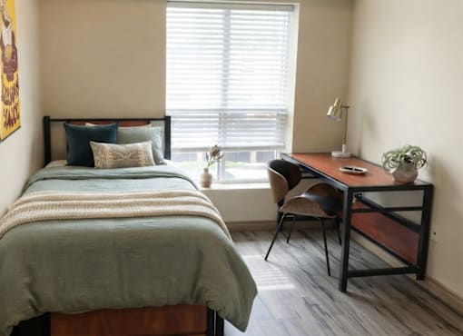 A bedroom with a bed, desk, and chair.