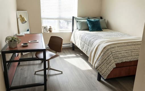 A bedroom with a bed, desk, and chair.