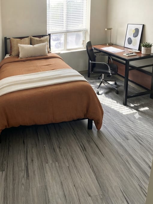 A bedroom with a bed, desk, and chair.