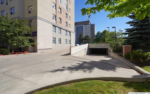 A parking lot in front of a building with a tall tree on the right.