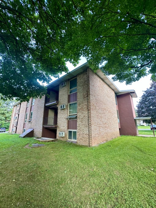 a brick building with grass and trees in front of it