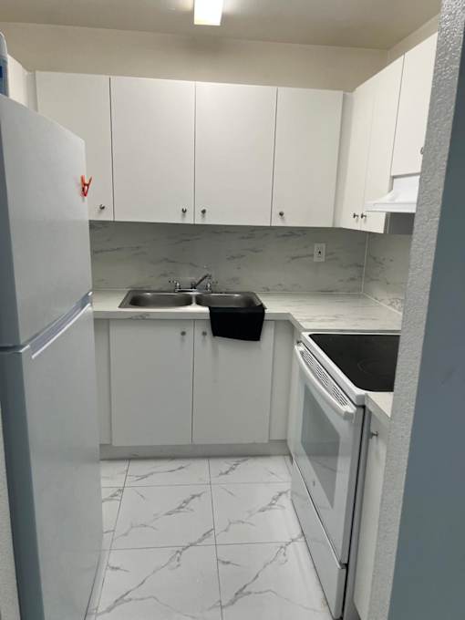 A kitchen with white cabinets and a marble floor.
