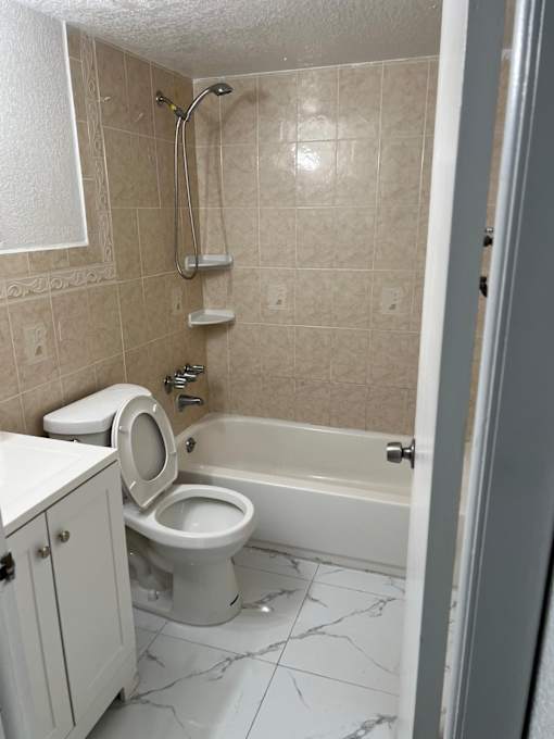 A white toilet sits in a bathroom with a marble floor.