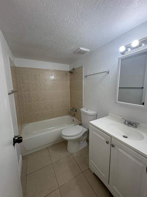 A white bathroom with a toilet, sink, and bathtub.
