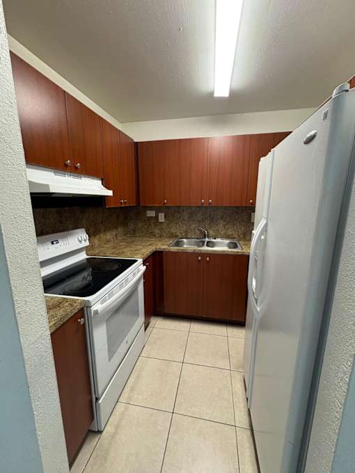 A kitchen with brown cabinets and a white refrigerator.