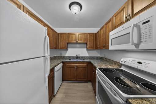 A kitchen with a white refrigerator, microwave, and stove.