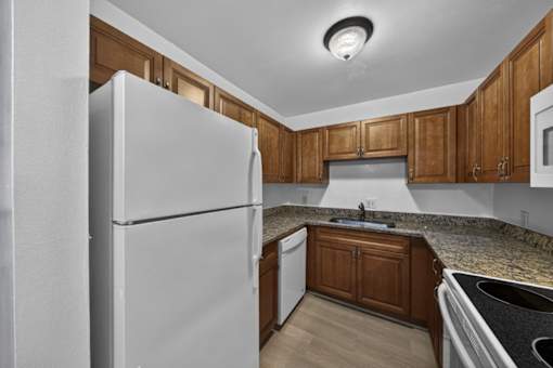 A kitchen with a white refrigerator and wooden cabinets.