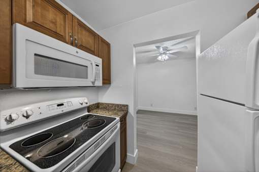 A kitchen with a white oven, microwave, and refrigerator.