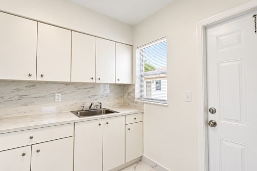 A kitchen with white cabinets and a marble countertop.