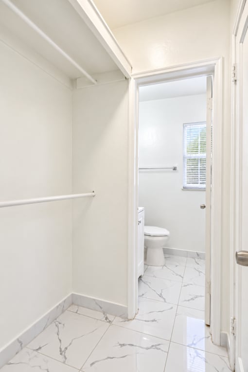 A white bathroom with a toilet and a marble floor.