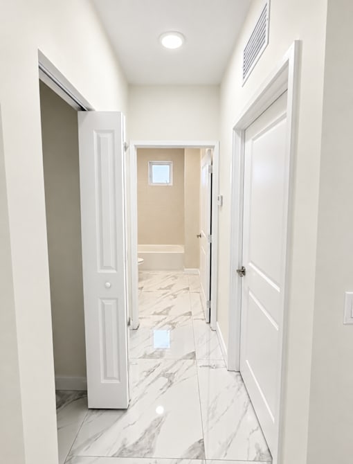 A hallway with marble floors and white doors.