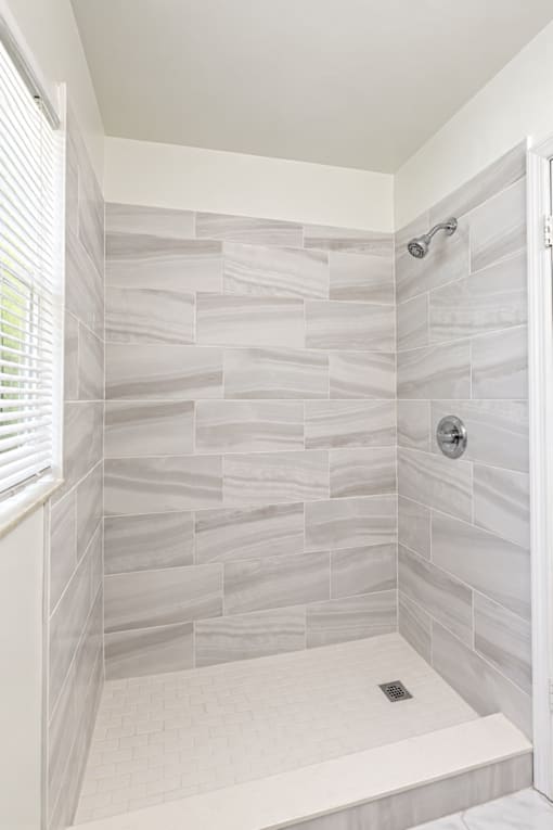 A bathroom with a shower area and a white tile floor.