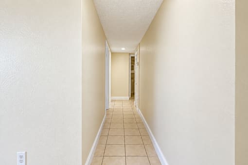 A long hallway with tiled floors and white walls.