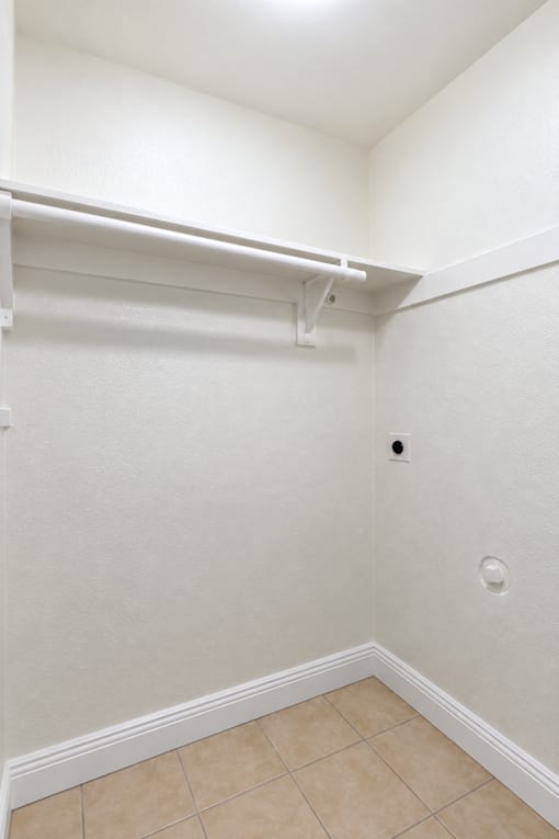 A white closet with a white shelf and a white tile floor.
