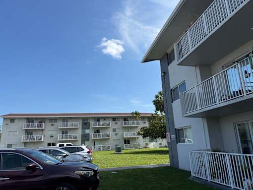 A row of cars parked in front of apartment buildings.