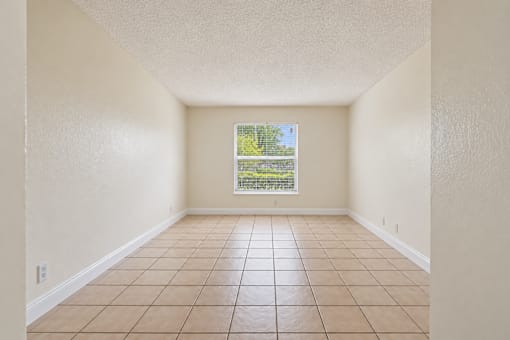 A room with a window showing a view of trees.